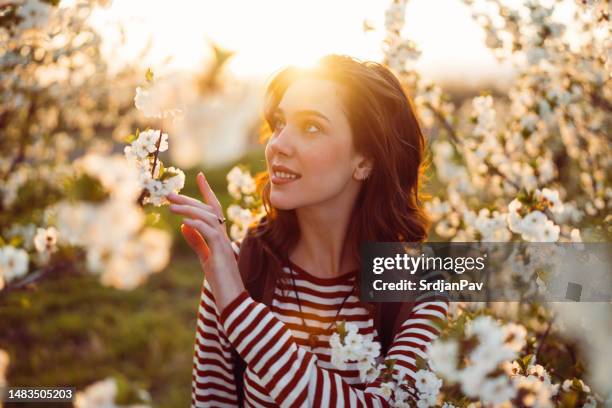 beautiful young woman enjoying carefree spring day in blossoming orchard - april 22 stock pictures, royalty-free photos & images