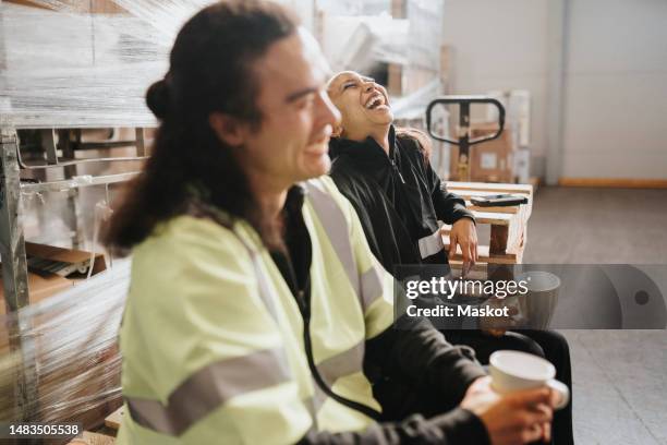 mature female worker having fun with colleague during coffee break at warehouse - working class stock pictures, royalty-free photos & images