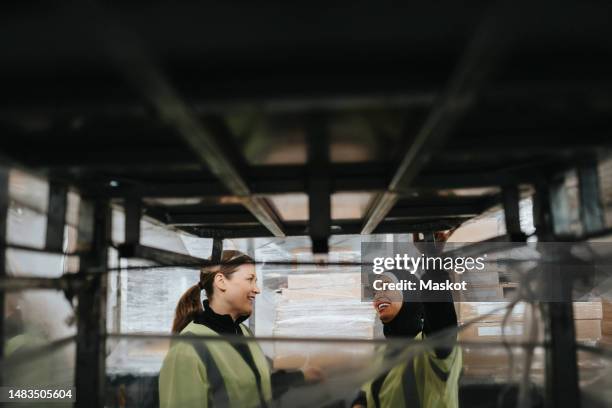 smiling female workers talking to each seen through rack at warehouse - rack stock pictures, royalty-free photos & images