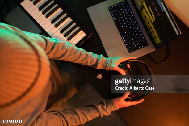 unrecognizable man holding headphones with his hands in a music studio - electric piano stock pictures, royalty-free photos & images