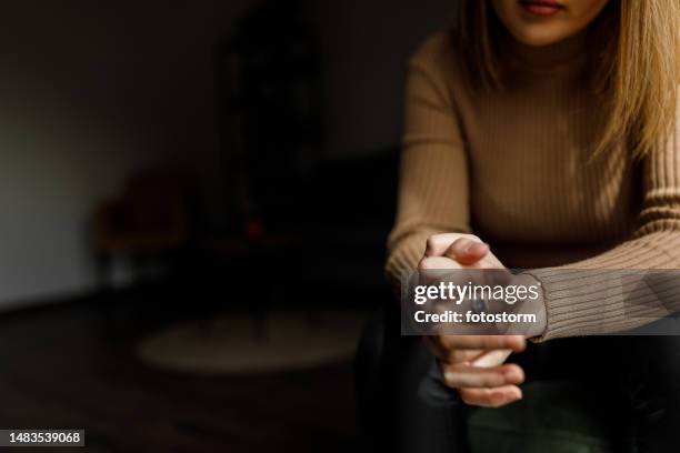 young woman anxiously cracking her knuckles, struggling with negative emotions - dust dark bildbanksfoton och bilder