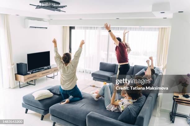 a group of friends watches tv and rejoices. black screen mockup. the concept of fans of sports games. - familia futbol tv fotografías e imágenes de stock