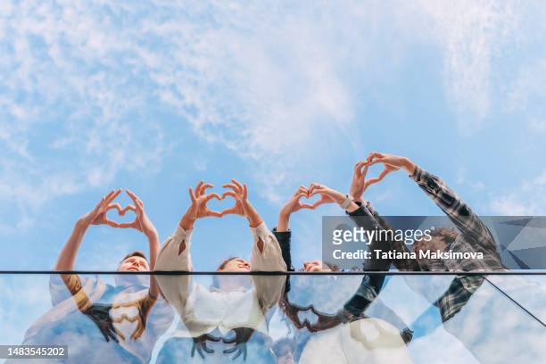 four people make hearts out of their fingers against the sky. copy space. - make a difference bildbanksfoton och bilder