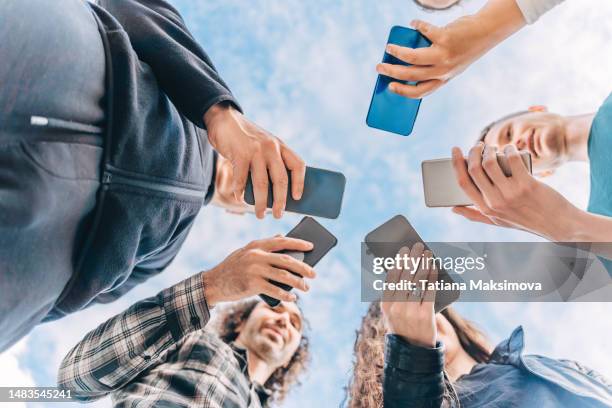 a group of friends with phones in their hands against the sky. view from below. - content strategy stock pictures, royalty-free photos & images