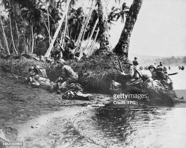 Soldiers from Company B, 172nd Infantry Regiment, 43rd Infantry Division of the XIV Corps, United States Army shelter behind palm tree trunks after...