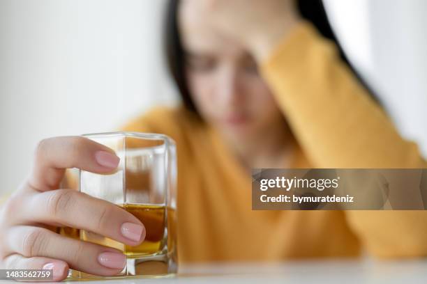 bevitore donna sconvolta alcolista seduta con bere whisky da solo - alcol antisettico foto e immagini stock