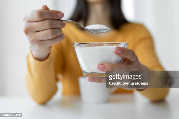 femme ajoutant du sucre raffiné à une tasse de café - blood sugar test photos et images de collection