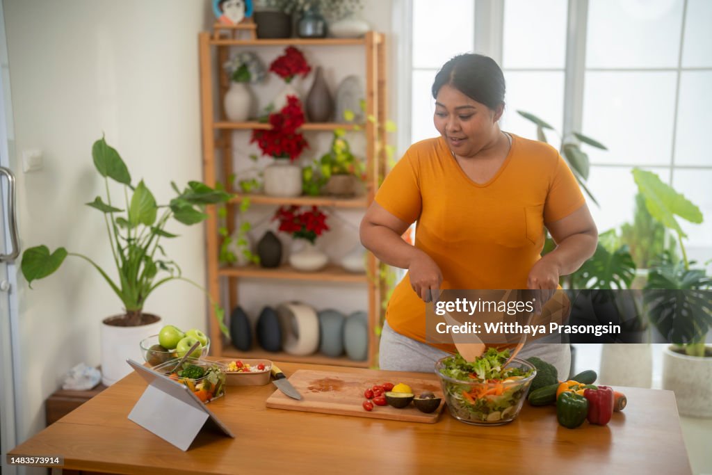 Plus size , caucasian woman learning to make salad and healthy food from social media