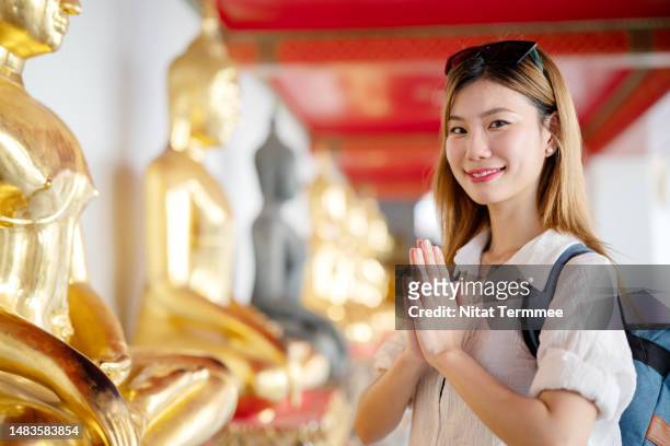 traveling makes your mind calm and more positive. portrait of a korean woman traveler paying homage and prostration to the buddha for making a wish during vacation at wat pho, bangkok, thailand. - prayer pose greeting stock-fotos und bilder