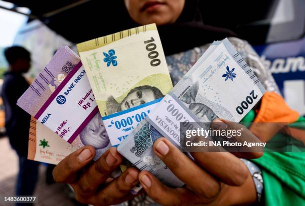 Woman shows small rupiah denominations from the Drive Thru system exchange at a mobile cash service in Medan, North Sumatra Province, Indonesia on...