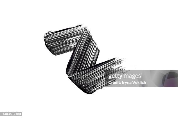 black smear mascara in the shape of a zigzag on white background, isolated. cosmetic make-up products for eyelashes. - mascara stockfoto's en -beelden