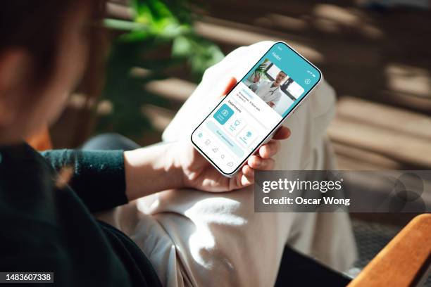 young woman having a virtual medical appointment via smartphone - telefonberatung stock-fotos und bilder