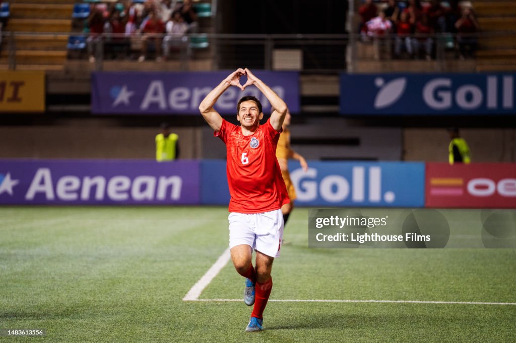 Male soccer player forms heart shape with his hands while celebrating goal