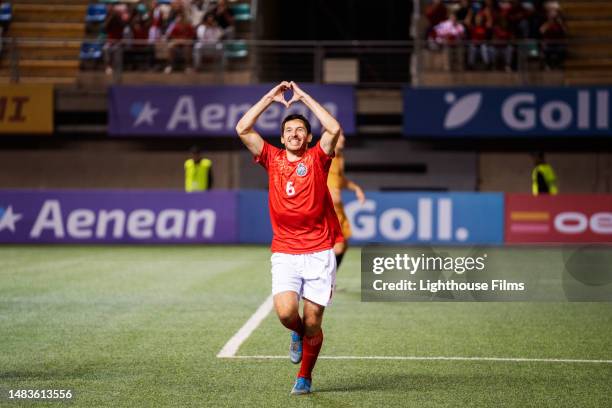 male soccer player forms heart shape with his hands while celebrating goal - live broadcast stock pictures, royalty-free photos & images