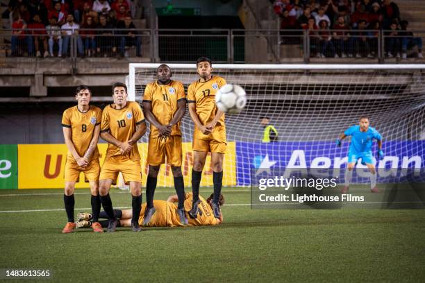 professional soccer players form a free kick wall before ball heads toward them - defender soccer stock pictures, royalty-free photos & images