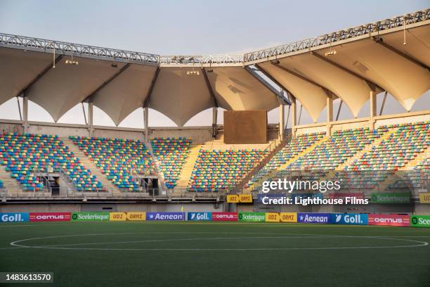 still photograph of an empty soccer stadium with colorful seating and advertising banners - empty bleachers foto e immagini stock