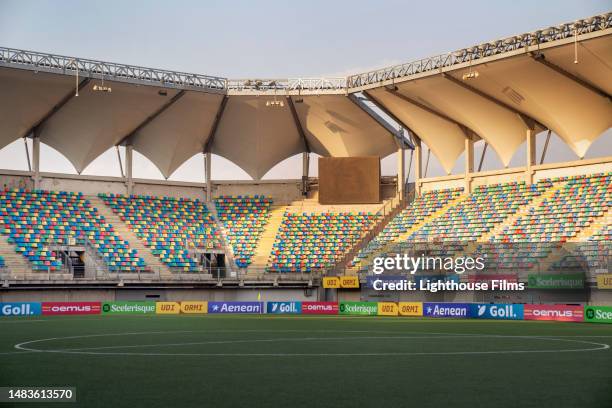 still photograph of an empty soccer stadium with colorful seating and advertising banners - soccer stadium stock pictures, royalty-free photos & images