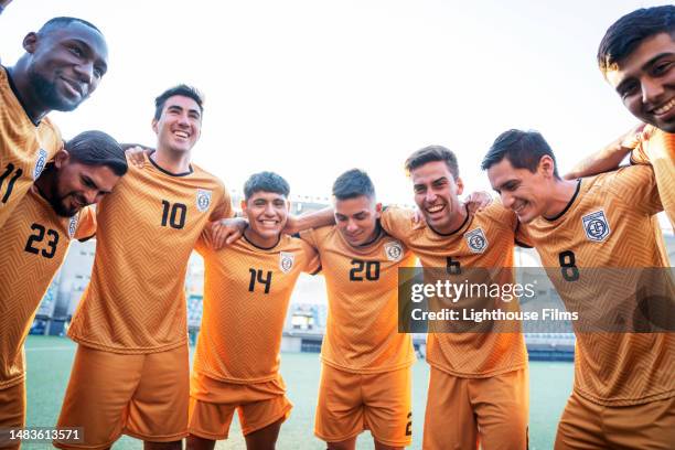 team of professional male soccer players join in a huddle to prepare for match - pre game huddle stock pictures, royalty-free photos & images