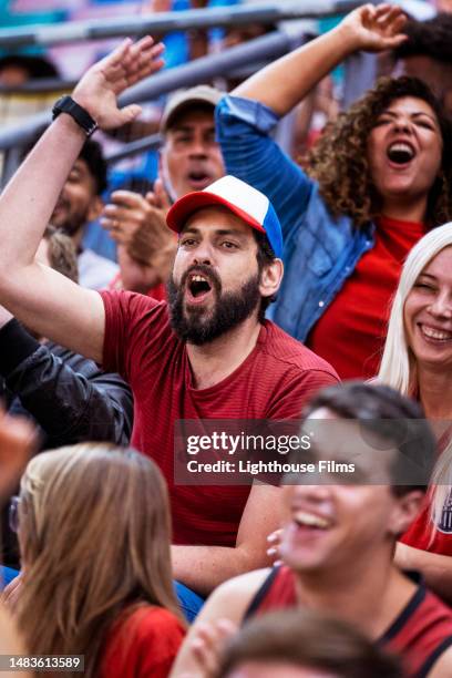 stressed fan sitting in audience shouts and raises hand to reaction to a call during a soccer match - surprise stadion stock-fotos und bilder