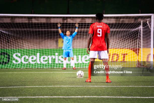 professsional goalie stands prepared to defend goal from opponent with ball in front of him - aftrappen stockfoto's en -beelden