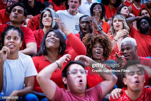 shocked audience of sports fans groan and throw their hands up in response to game play - surprise stadion stock-fotos und bilder