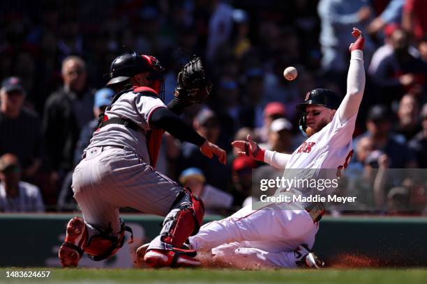 Alex Verdugo of the Boston Red Sox slides past Christian Vazquez of the Minnesota Twins to score a run during the third inning at Fenway Park on...