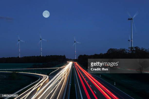wind turbines and country road at blue hour - vehicle light fotografías e imágenes de stock