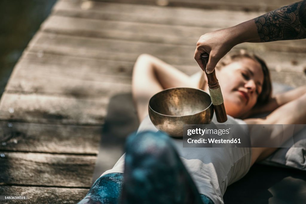 Therapist playing Tibetan singing bowl for customer lying down