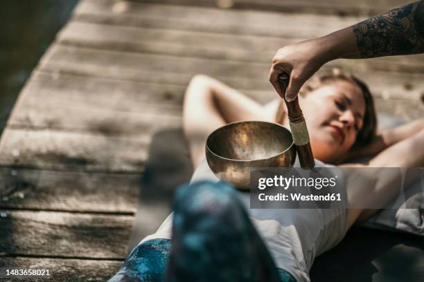 therapist playing tibetan singing bowl for customer lying down - chinese herbal medicine stock pictures, royalty-free photos & images