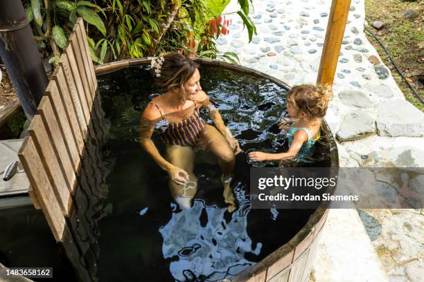 a young girl and her mother soaking in a wood fired hot tub. - drenched stock pictures, royalty-free photos & images