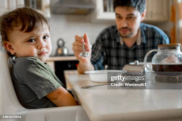 son refusing to eat food being fed by father at home - rebellion stock pictures, royalty-free photos & images