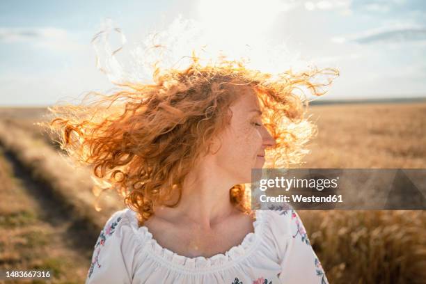 happy redhead woman tossing hair in field - haare schütteln stock-fotos und bilder