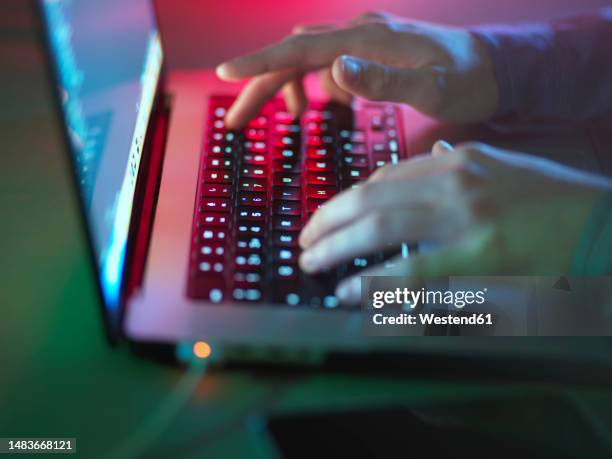 hacker typing on illuminated laptop keyboard at office - cyber harcèlement photos et images de collection