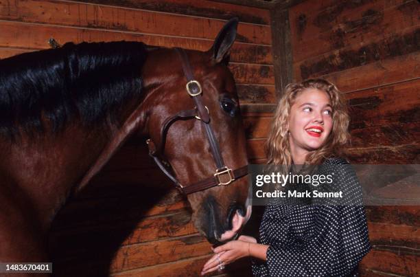 Actress Drew Barrymore poses with a horse for People Magazine in 1990 in Los Angeles