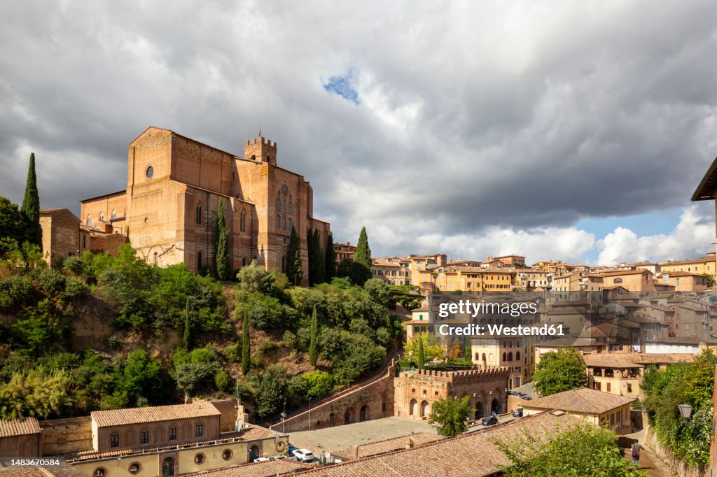 Italy, Tuscany, Siena, Thick clouds over Basilica of San Domenico and surrounding houses