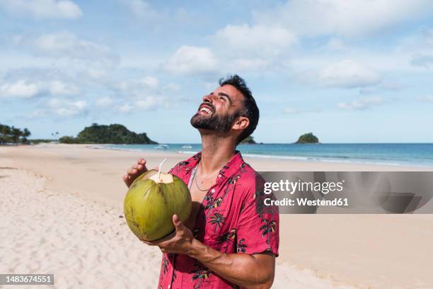 happy man standing with coconut water enjoying at beach - el nido - fotografias e filmes do acervo