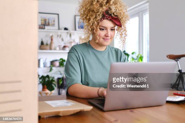 smiling businesswoman working on laptop at desk - sold palabra en inglés fotografías e imágenes de stock