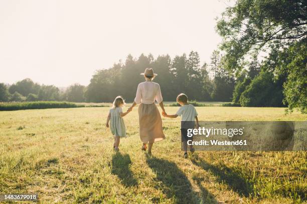 happy mother walking with son and daughter on sunny day - sunny back fotografías e imágenes de stock