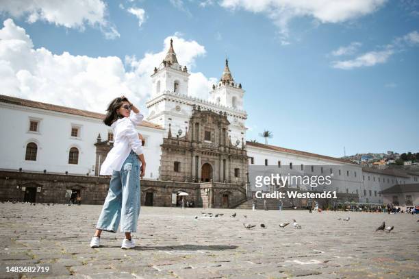 woman with hand in hair standing in front of plaza de san francisco - quito stock-fotos und bilder