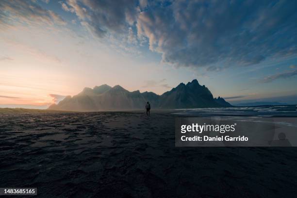 backpacker walking on stokksnes beach in iceland at sunset, landscape photography in famous places, wonderlust - wonderlust stock pictures, royalty-free photos & images