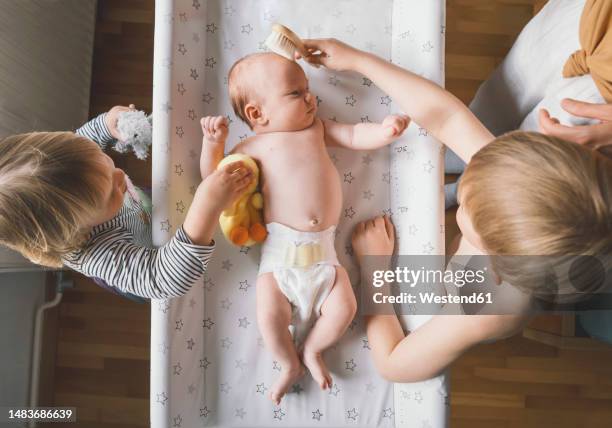 siblings helping mother in grooming of baby boy at home - adult baby boy diaper change foto e immagini stock