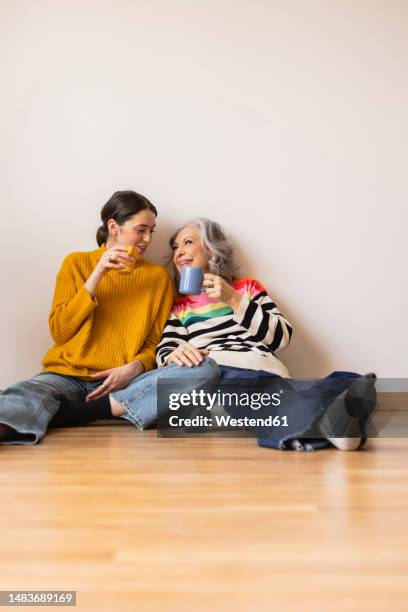 happy mother and daughter with coffee cup sitting on floor - mother daughter stock pictures, royalty-free photos & images