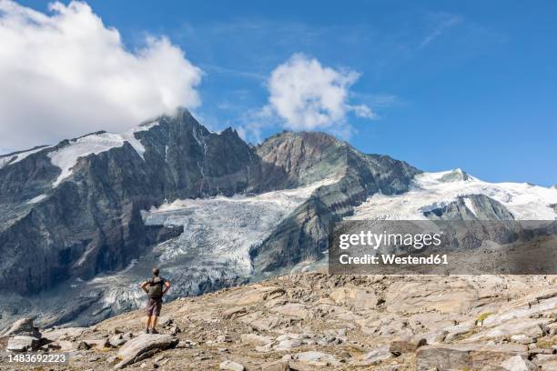 man with hand on hip looking at mountain, carinthia, austria - hohe tauern national park stockfoto's en -beelden