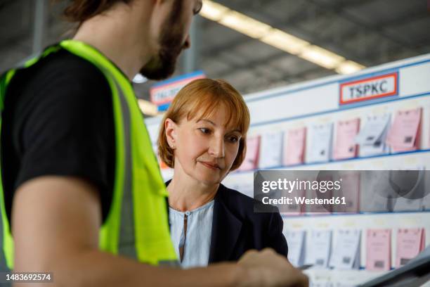 manger examining checklist by colleague in warehouse - manger stock pictures, royalty-free photos & images