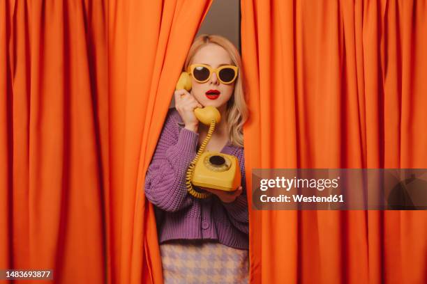 woman talking on yellow vintage landline phone - teléfono con cable fotografías e imágenes de stock