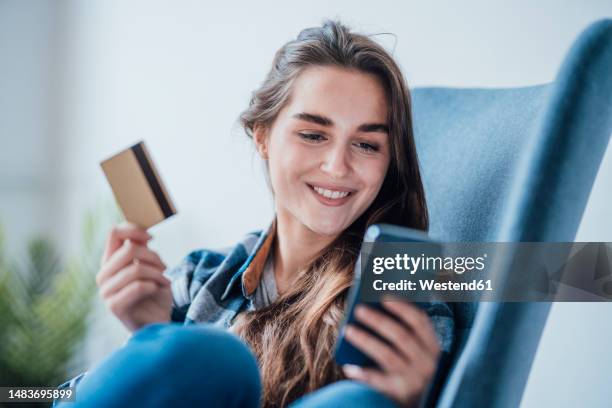 happy businesswoman using mobile phone and sitting with credit card - mobile payment stock pictures, royalty-free photos & images