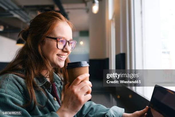 happy young freelancer with disposable coffee cup sitting in cafe - disposable imagens e fotografias de stock