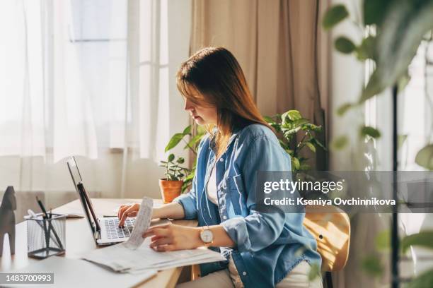 top view close up woman calculating bills, money, loan or rent payments, using laptop, online banking service, sitting at table, female holding receipt, planning budget, managing expenses, finances - energy bill stock pictures, royalty-free photos & images