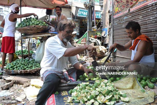 Indian labourers, who earn approximately 300 to 400 Indian rupees per day, cut raw mangoes which are used for pickles at the roadside in Amritsar on...