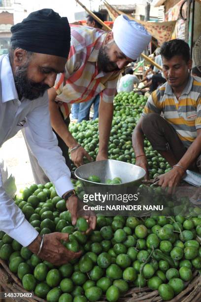 Indian Sikh customers buy raw mangoes which are used for pickles at the road side in Amritsar on July 15, 2012. Although India is the world's largest...